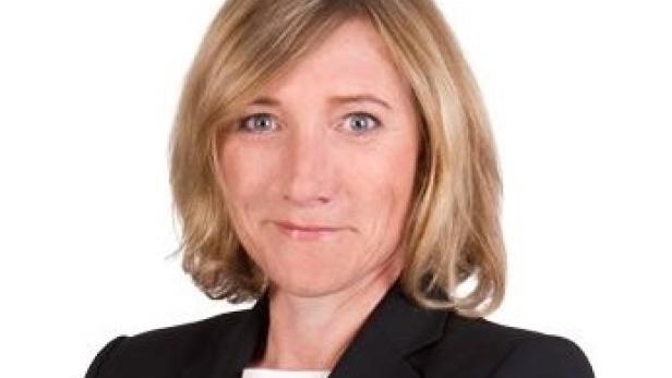 Porträt einer Frau mit blonden Haaren und einem schwarzen Blazer.