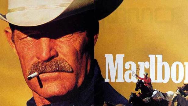 Ein Cowboy mit Hut und Zigarette vor dem Schriftzug „Marlboro“ und einer Pferdeherde.