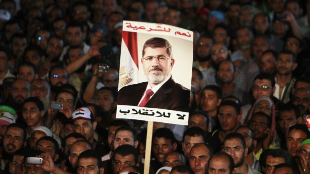 Supporters of deposed Egyptian President Mohamed Mursi hold up a poster of Mursi during a protest at the Rabaa al-Adawiya square where they are camping, in Cairo, August 6, 2013. The chances for a negotiated end to Egypt&#039;s political crisis looked to have hit the rocks on Tuesday with the army-installed government reportedly ready to declare that foreign mediation efforts had failed. It would also declare that Muslim Brotherhood protests against the army&#039;s overthrow of Mursi were non-peaceful - a signal that the government intends to end them by force. The poster reads, &quot;Yes to legitimacy, no to the coup.&quot; REUTERS/Mohamed Abd El Ghany (EGYPT - Tags: POLITICS CIVIL UNREST)