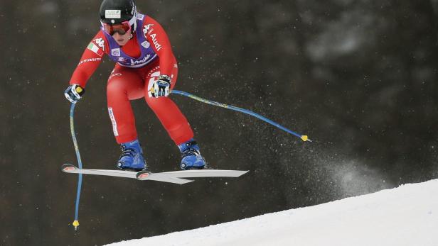 Eine Skirennläuferin springt während eines Rennens über eine Kuppe.
