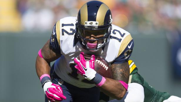 Ein Footballspieler der Los Angeles Rams mit pinkfarbenen Accessoires trägt den Ball.