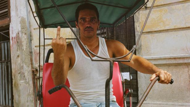 Ein Mann auf einer Fahrradrikscha zeigt den Stinkefinger.