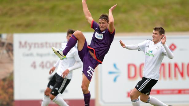 Ein Fußballspieler springt, um den Ball mit dem Fuß zu spielen, während andere Spieler zusehen.