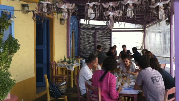 Customers eat lunch under fresh octopus in a restaurant at the volcanic island of Santorini in this September 10, 2011 file photo. Greece is struggling under a mountain of debt, violent street protests erupt in the capital Athens, and world financial markets fear Greece will exit the euro zone. But Greece is still a great place to visit - just head to its idyllic islands. Reuters correspondents with local knowledge help visitors explore Paros and Santorini. Picture taken September 10, 2011. To match Travel Postcard: TRAVEL-GREECE/ISLANDS. REUTERS/Michael Perry (GREECE - Tags: TRAVEL SOCIETY)