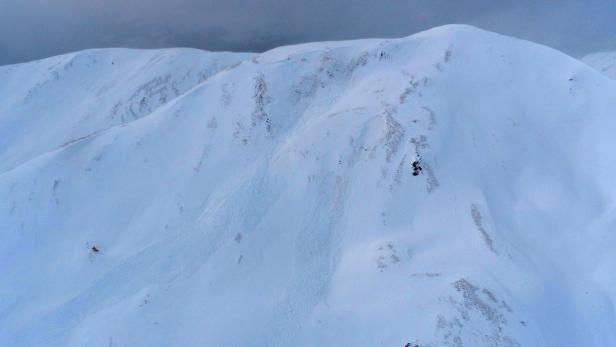 Eine verschneite Berglandschaft unter einem bewölkten Himmel.