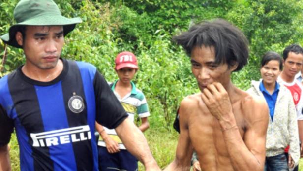Ein Mann im Inter Mailand-Trikot führt eine abgemagerte Person durch den Dschungel.