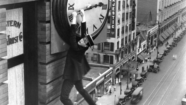 Harold Lloyd hängt an einem Uhrzeiger hoch über einer belebten Straße.