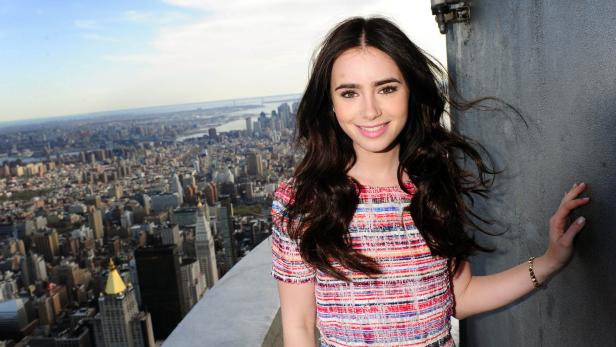 Lily Collins posiert vor der Skyline von New York City.