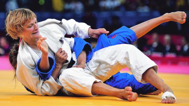 Eine Judoka in einem weißen Judoanzug kämpft am Boden gegen eine Gegnerin.