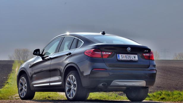 Ein dunkler BMW X4 steht auf einer Landstraße.