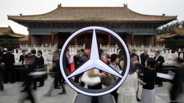 Ein Mercedes-Stern steht vor einem traditionellen chinesischen Gebäude, umgeben von Menschen.