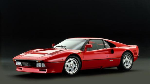 Ein roter Ferrari 288 GTO vor einem dunklen Hintergrund.