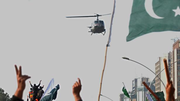 epa03536593 A security helicopter hovers over the supporters of Tahir ul Qadri, a prominent religious scholar, shout slogans during a sit-in protest in Islamabad, Pakistan, 15 January 2013. Thousands of supporters of Tahir ul Qadri, who started his march from the eastern city of Lahore 13 January, reached Islamabad on 15 January, to demand political reforms. Tahir ul Qadri, wants authorities to implement election reforms ahead of a parliamentary vote which should be held within 60 days after the term of the current assembly expires in March 2013. EPA/W. KHAN