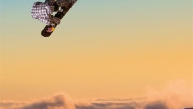 Ein Snowboarder springt vor dem Hintergrund eines Sonnenuntergangs über eine Wolkendecke.