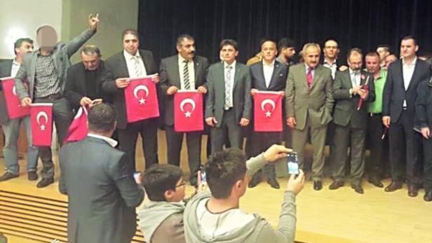 Turan Yaldir (re. am Podium) mit Avrasya-Mitgliedern, von denen eines den faschistischen Wolfsgruß zeigt