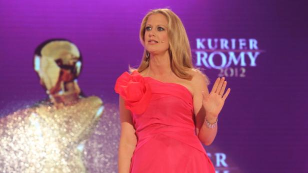 Eine blonde Frau in einem roten Kleid auf der Bühne der Romy-Preisverleihung 2012.
