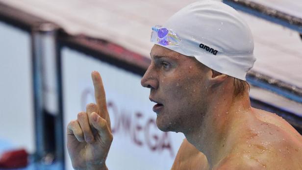 Ein Schwimmer mit Badekappe und Schwimmbrille reckt den Zeigefinger in die Höhe.
