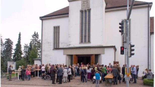 Eine Menschenmenge versammelt sich vor einer Kirche.