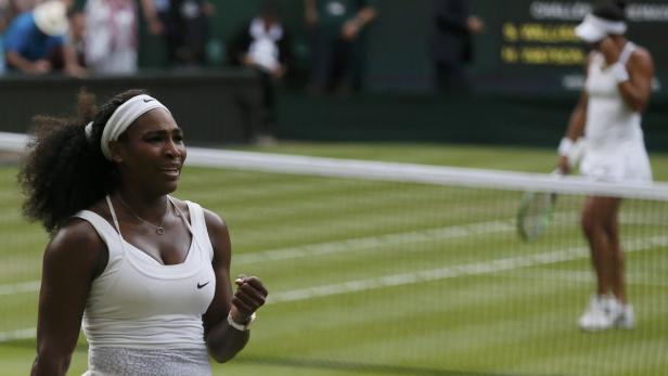 Serena Williams bei einem Tennisspiel, mit einer Faust geballt vor dem Netz.