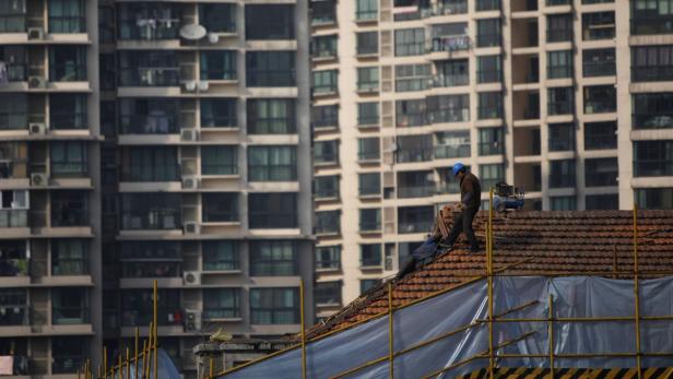 A labourer works on the top of a building in Shanghai January 18, 2013. China&#039;s economy regained speed in the final quarter of 2012, pulling out of a post-global financial crisis downturn that produced the slowest year of economic growth since 1999. Evidence of a burgeoning recovery in exports, stronger than expected industrial output and retail sales, together with robust fixed asset investment, all signalled that Beijing&#039;s pro-growth policy mix has gained sufficient traction to underpin a revival without yet igniting inflationary risks. REUTERS/Aly Song (CHINA - Tags: BUSINESS CONSTRUCTION)