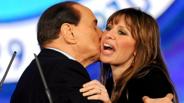 Silvio Berlusconi gibt einer Frau einen Kuss auf die Wange.