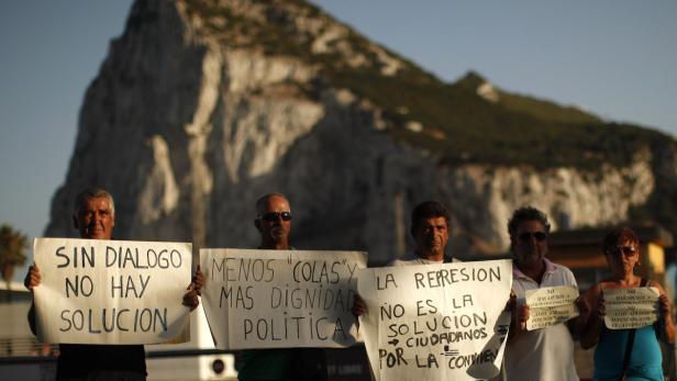 Spanish workers of the association of Spanish workers in Gibraltar (ASCTEG) and unemployed people pose for a photo as they hold signs in front of the Rock of the British territory of Gibraltar (rear), a monolithic limestone promontory, at the border in La Linea de la Concepcion, southern Spain August 6, 2013. Tensions over Gibraltar escalated on Monday when the British territory&#039;s chief minister accused Spain of &quot;sabre-rattling&quot; and behaving like North Korea after Madrid floated the idea of a new border crossing fee and airspace controls. The signs (L-R) read, &quot;Without dialogue there is no solution. Less queues and more political dignity. Repression is not the solution, citizens for the coexistence. No more abuses to innocents. Not to intentioned delays at the border&quot;. REUTERS/Jon Nazca (SPAIN - Tags: POLITICS TPX IMAGES OF THE DAY)