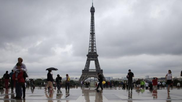 Tourists stroll on the Trocadero square, in front of the Eiffel Tower during a rainy summer day in Paris, August 7, 2013. REUTERS/Christian Hartmann (FRANCE - Tags: CITYSPACE SOCIETY TRAVEL)