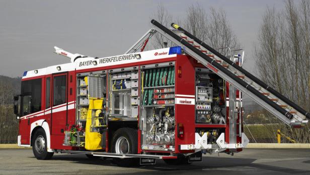 Ein rotes Feuerwehrfahrzeug der Bayer Werkfeuerwehr mit geöffneten Fächern und einer Leiter.