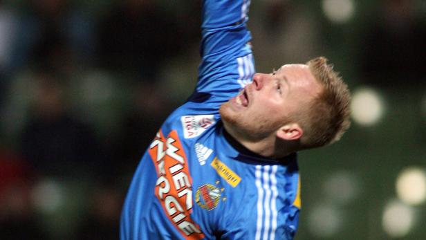 Ein Fußballspieler in blauem Trikot jubelt mit erhobenem Arm.