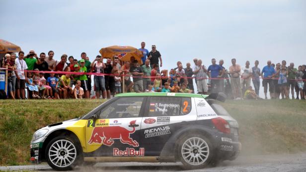 Ein Rallyeauto mit Red Bull-Aufdruck fährt an einer Zuschauermenge vorbei.