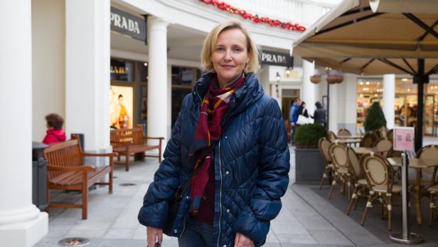 Eine Frau mit Einkaufstüten vor einem Prada-Geschäft.