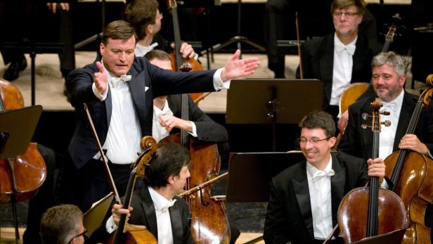 Ein Dirigent leitet ein Orchester mit Cellisten.