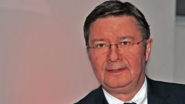 Porträt eines Mannes mit Brille und dunklem Anzug.