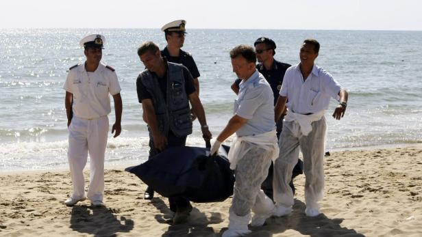 ATTENTION EDITORS - VISUAL COVERAGE OF SCENES OF DEATH AND INJURY Italian police carry the body of a migrant who drowned after a shipwreck, at La Playa beach in Catania on Sicily island August 10, 2013. The bodies of six migrants were recovered on the beach after a boat carrying close to 120 migrants ran aground about 15m (49 ft) from shore. Dozens of other passengers have been rescued, according to news reports. REUTERS/Antonio Parrinello (ITALY - Tags: DISASTER MARITIME SOCIETY IMMIGRATION)