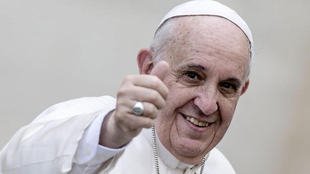 Papst Franziskus lächelt und zeigt den Daumen nach oben.