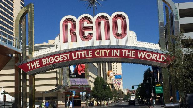 Das leuchtende „Reno“-Schild, das als „The Biggest Little City in the World“ bekannt ist, überspannt eine belebte Straße.