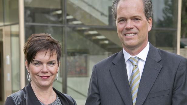 Eine Frau und ein Mann in formeller Kleidung stehen nebeneinander.