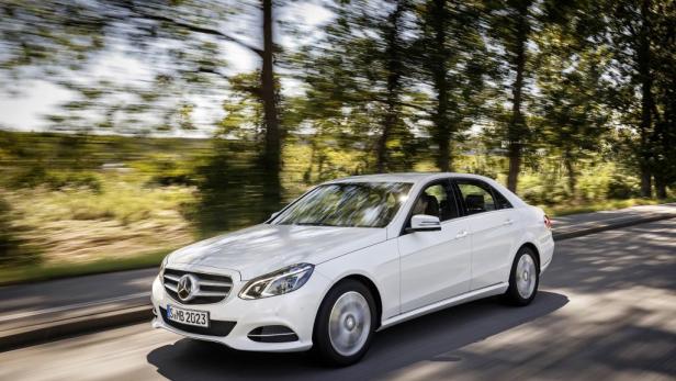 Ein weißer Mercedes-Benz E-Klasse fährt auf einer Landstraße.