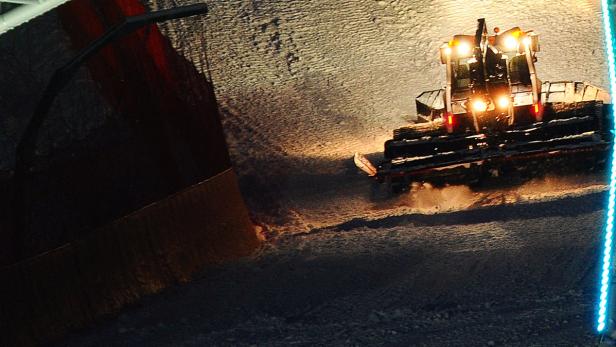 Ein Pistengerät präpariert eine Skipiste bei Nacht.