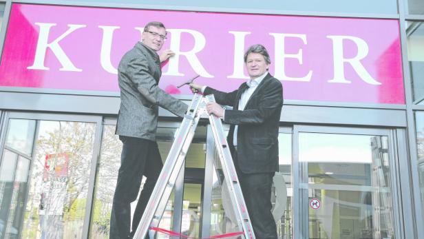 KURIER-Geschäftsführer Thomas Kralinger und Chefredakteur Helmut Brandstätter befestigen den KURIER-Schriftzug auf dem neuen Haus.