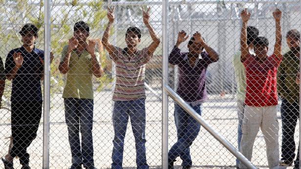 epa03200644 Immigrants stand behind the fence of the first illegal migrant detention center, in Amygdaleza township, north of Athens, Greece, 29 April 2012. The first of 30 recently announced illegal migrant detention centres was opened on 29 April in the Amygdaleza township, north of Athens, inside the perimeter of a police academy. According to initial reports, a total of 56 foreign nationals - all identified as illegal immigrants - were transferred to the new facility. EPA/PANTELIS SAITAS
