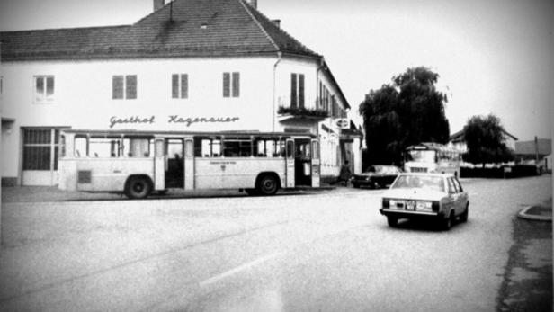 Ein Bus hält vor dem „Gasthof Hagenauer“ in einer Schwarzweißaufnahme.