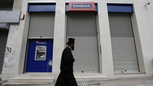 A Greek Orthodox priest walks past a closed Postbank branch during a 24-hour strike of bank employees in Athens October 24, 2012. Greece is seeking to cut its debt mountain by reducing the interest and extending the maturities of its bailout loans, the country&#039;s finance minister Yannis Stournaras said on Wednesday. REUTERS/Yorgos Karahalis (GREECE - Tags: POLITICS BUSINESS EMPLOYMENT CIVIL UNREST RELIGION)
