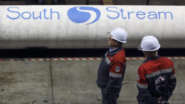 Zwei Arbeiter mit Schutzhelmen stehen vor einer Pipeline mit der Aufschrift „South Stream“.