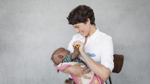 Eine Frau hält ein Baby im Arm und lächelt es an.