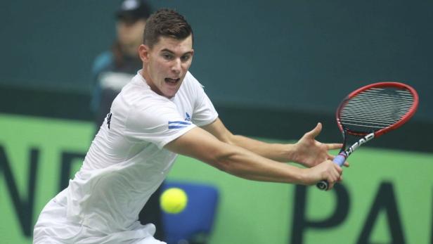 Ein Tennisspieler schlägt einen gelben Tennisball mit seinem Schläger.