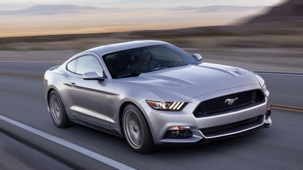 Ein silberner Ford Mustang fährt auf einer Landstraße.