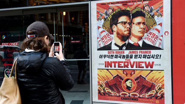 Eine Frau fotografiert ein Filmplakat von „The Interview“ mit Seth Rogen und James Franco.