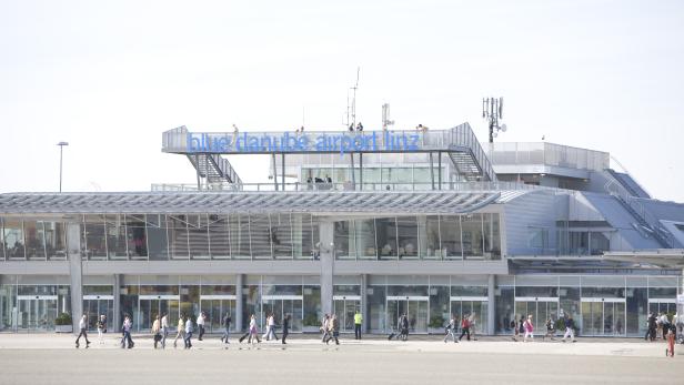Das Terminal des Blue Danube Airport Linz mit Passanten im Vordergrund.