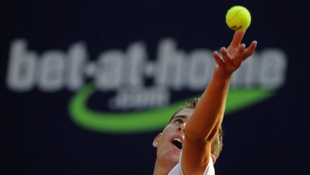 Ein Tennisspieler balanciert einen Ball auf seinem Finger vor einem „bet-at-home“-Logo.
